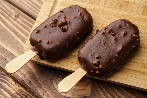 Chocolate cake pops ice creams on wooden board close up photo