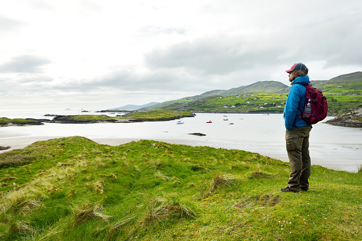 Male tourist admiring the Abbey Island, the idyllic patch of land in Derrynane Historic Park, famous for ruins of Derrynane Abbey and cemetery, located in County Kerry, Ireland
