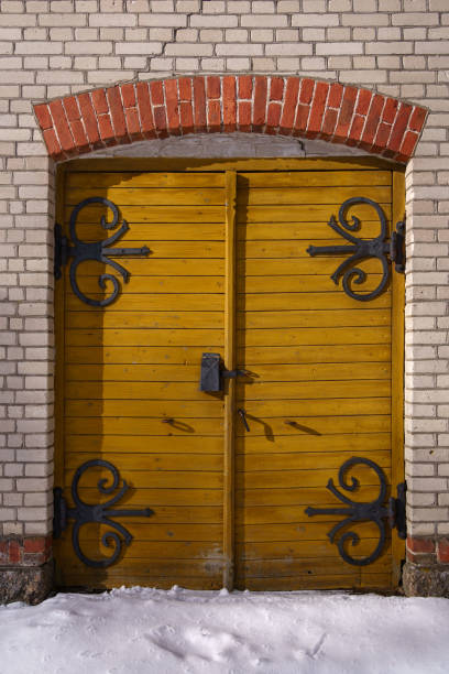 Yellow old wooden double doors on a brick wall in winter.