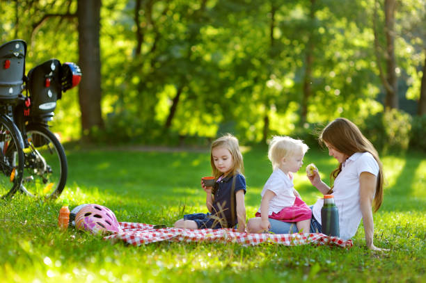 Young mother and her daughters picnicking in the park