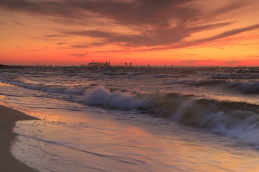 Beautiful sunset on the beach in Górki Zachodnie in Gdansk Rough waves on the sandy shore.