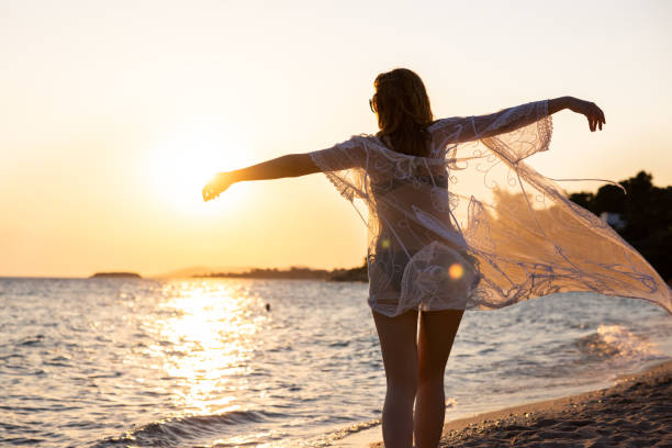 istock With raised arms, unrecognizable young woman admiring the sunset while dancing on the beach 1502960054