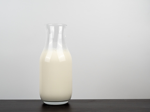 A bottle of milk on a wooden table. A bottle of milk on a light background.