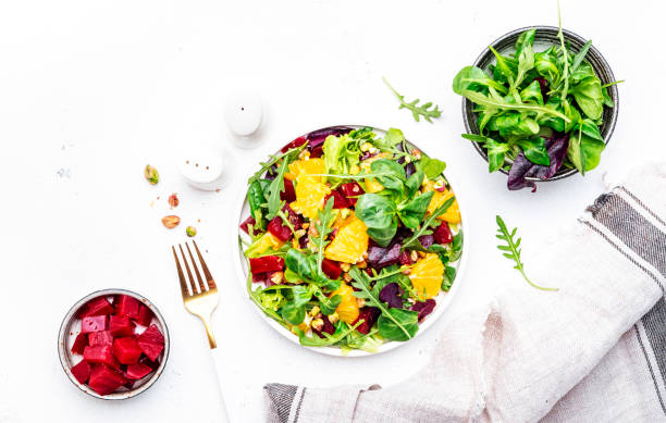 istock Beetroot and orange salad with arugula, lamb lettuce, mini chard and pistachios, white table, copy space.. Fresh useful dish for healthy eating 1502962454