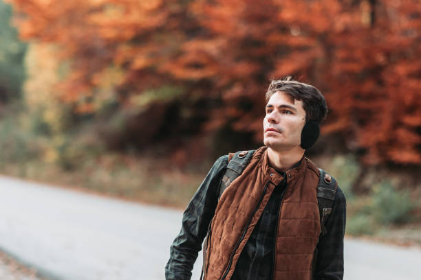Young man with backpack in the woods. Autumn colors. Copy space