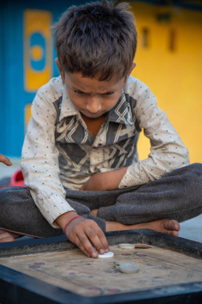 istock Young Indian boy kid practicing or playing Carrom board at his village home 1502967390