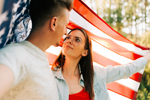 Young couple wrapped with American flag celebrating Independence day