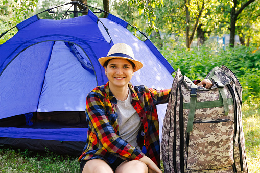 Woman tent summer. Defocus young woman sitting near camping tent outdoors surrounded by beautiful nature. Freelance, sabbatical, mental health. Rest. Summer camp. Dream. Out of focus.
