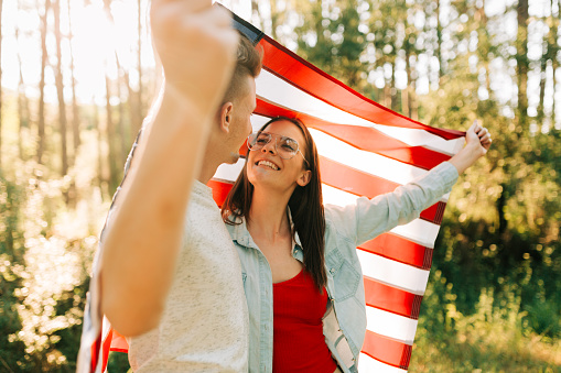 Young couple wrapped with American flag celebrating Independence day