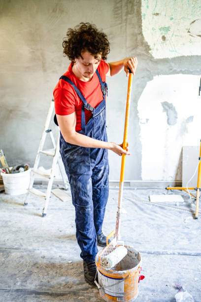 istock Construction worker painting apartment walls with paint roller 1502969234