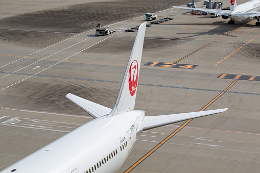 Tail of Japan Airlines Boeing 787-9 Dreamliner aircraft with registration JA878J parked at gate at Tokyo Haneda International Airport in May 2023.