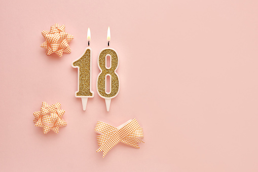 Number 18 on a pastel pink background with festive decorations. Happy birthday candles. The concept of celebrating a birthday, anniversary, important date, holiday. Copy space. banner