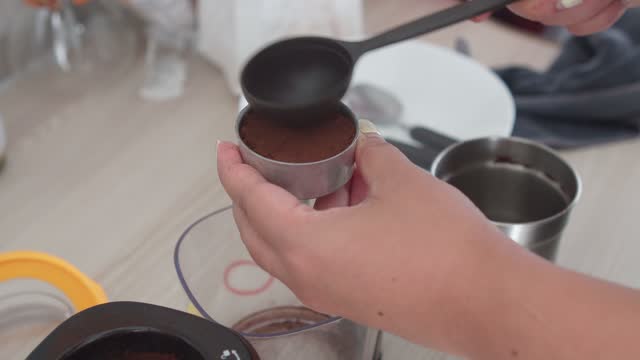 a person pouring ground coffee into a moka pot.