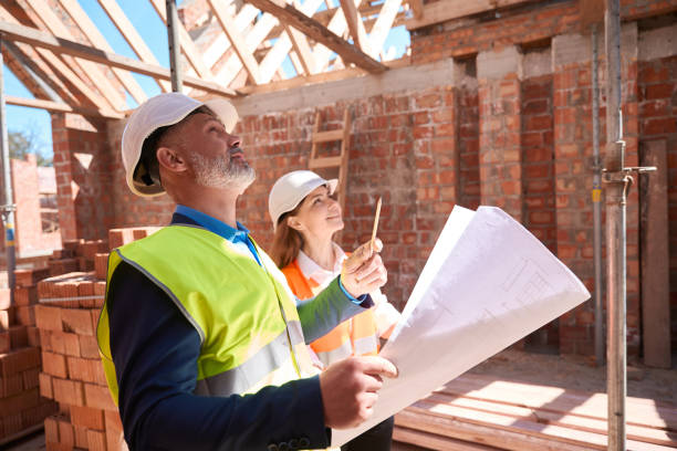 Building inspectors holding project, checking quality of roof construction