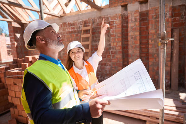 istock Building engineers in hardhats discussing roof construction looking at blueprint 1502974751