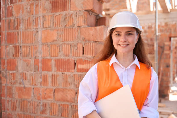 istock Woman architect holding laptop and smiling standing on construction site 1502974771