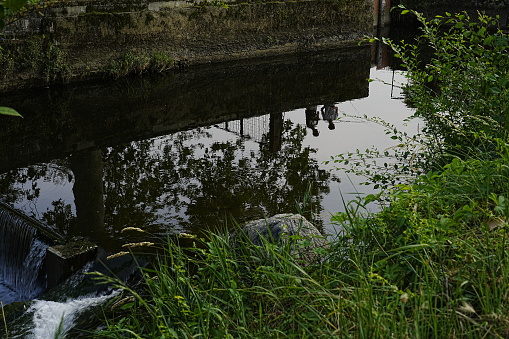 fishermen reflected in the water of a canal
