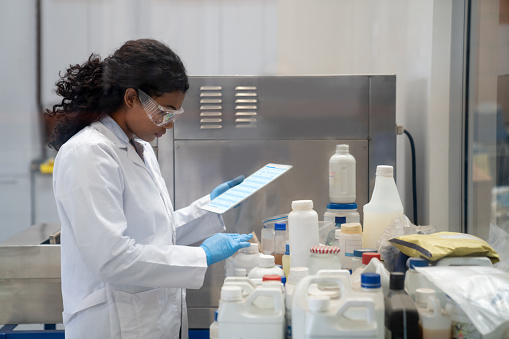 Latin American female chemist doing research while working at an industrial lab using a digital tablet