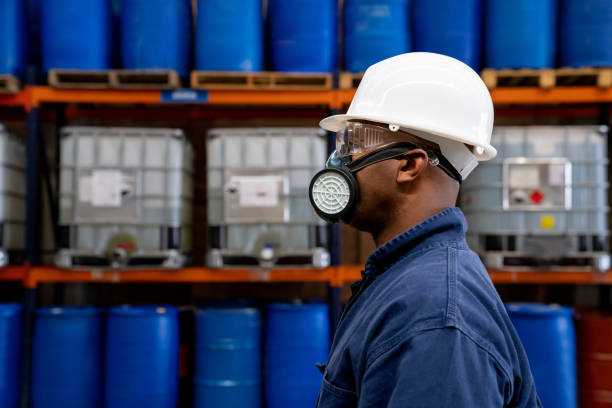 Chemical plant worker wearing a gas mask and protective workwear Profile view of an African American chemical plant worker wearing a gas mask and protective workwear at work man wearing a barrel stock pictures, royalty-free photos & images