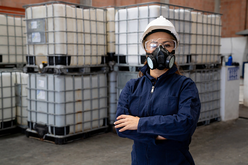 Portrait of a Latin American woman working at a chemical plant wearing protective workwear and looking at the camera