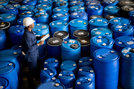 Chemical plant worker doing a stock inventory of barrels at a distribution warehouse
