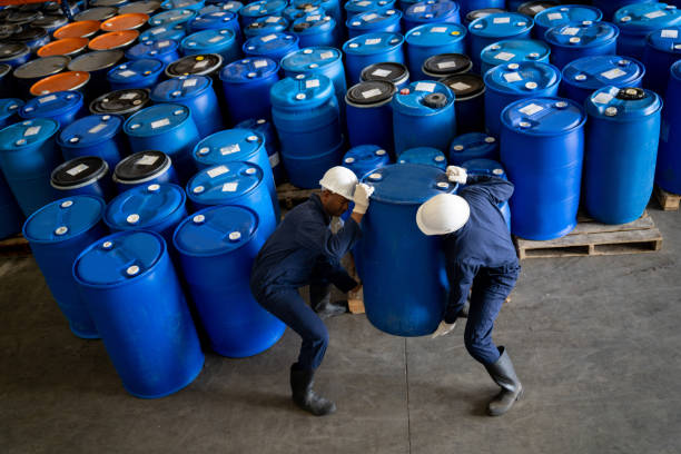 equipo de trabajadores que transportan barriles de sustancias químicas en un almacén - chemical worker fotografías e imágenes de stock