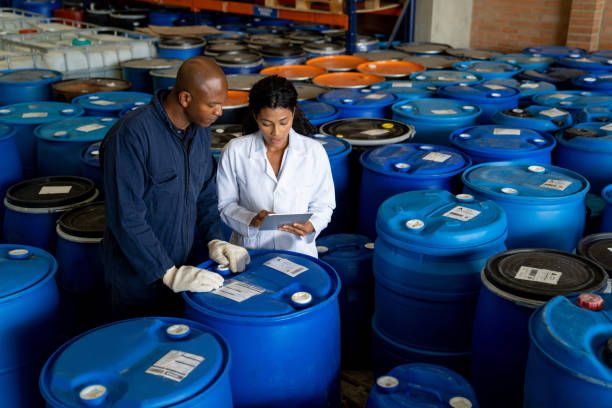 Foreperson talking to a blue-collar worker at a chemical plant Female foreperson talking to a blue-collar worker at a chemical plant while doing an inventory on some barrels man wearing a barrel stock pictures, royalty-free photos & images