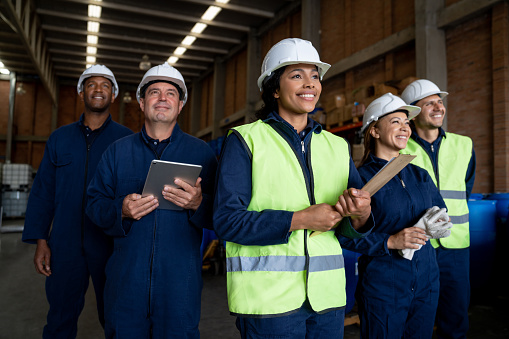 Happy goup of Latin American blue-collar workers smiling at a chemical plant and looking away