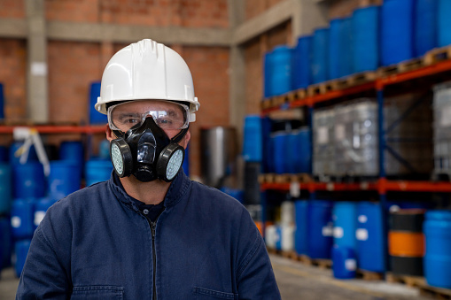Portrait of a chemical plant worker wearing a gas mask and protective workwear while looking at the camera
