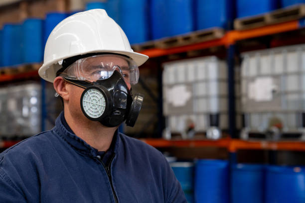 Chemical plant worker wearing a gas mask and protective workwear Portrait of a Latin American chemical plant worker wearing a gas mask and protective workwear at work man wearing a barrel stock pictures, royalty-free photos & images