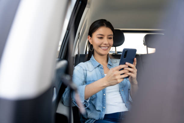 feliz compartilhamento de carro de passeio usando um aplicativo móvel em seu telefone celular - mobile phone seat belt text messaging smiling - fotografias e filmes do acervo