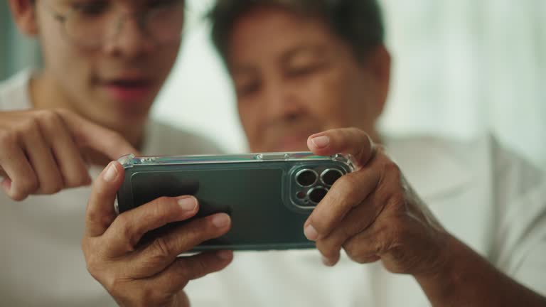 Senior woman enjoying game on mobile with young man.