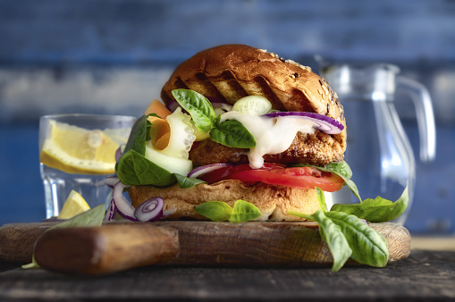 Close-up one burger with beef patty, vegetables and yogurt on wooden board, healthy food