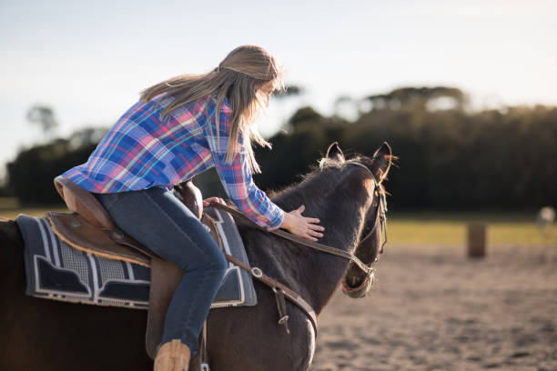 Woman sitting on a saddle caressing the horse's neck