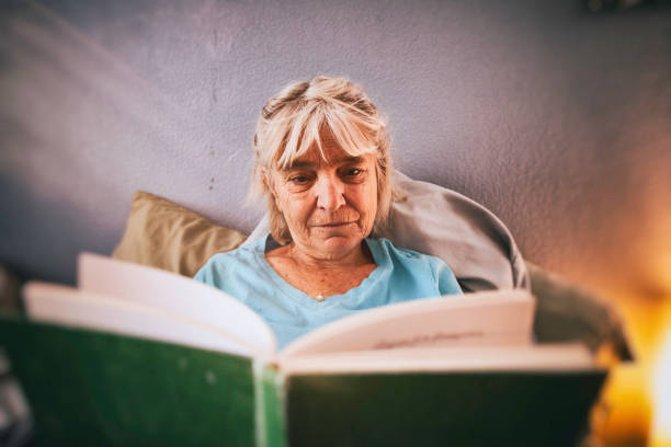 istock Beautiful elderly woman reading in bed by the window light 1503012231