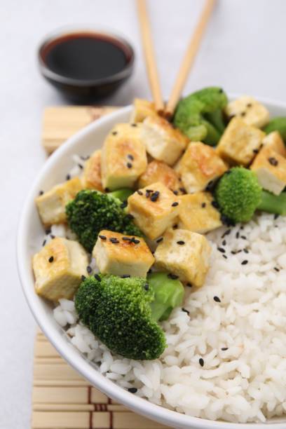 bol de riz avec tofu frit et brocoli sur table blanche, gros plan - tofu chinese cuisine vegetarian food broccoli photos et images de collection