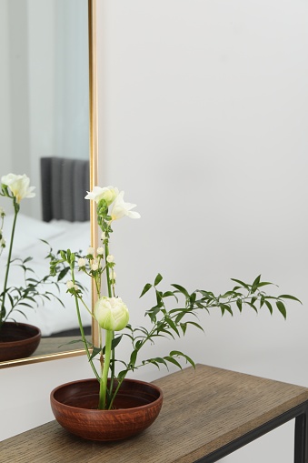 Stylish ikebana with beautiful flowers and green branch carrying cozy atmosphere at home