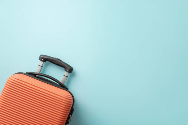 istock Dreamy summer trip. Orange suitcase seen from top view on a pastel blue background, offering space for text or advertising 1503016483