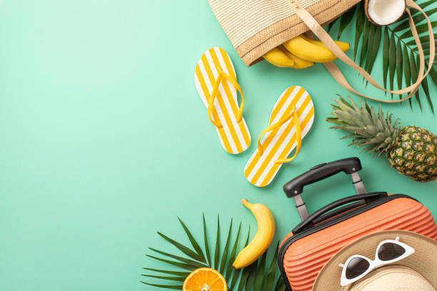 istock The excitement of upcoming summer vacation. Top view composition featuring suitcase, beach accessories, glasses, hat, flip-flops, palm leaves, exotic fruits, teal backdrop. Empty space for text or ad 1503016616