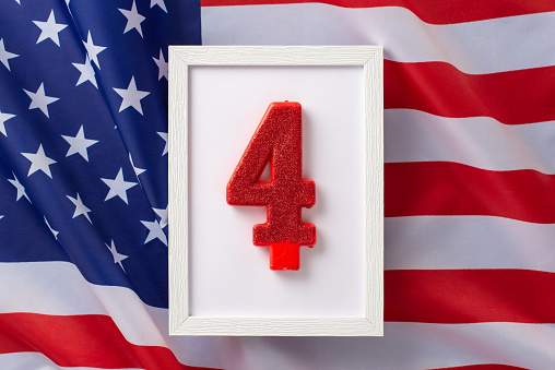 Fourth of July celebration concept. Top view photo of white wooden frame with the number four on american flag isolated background