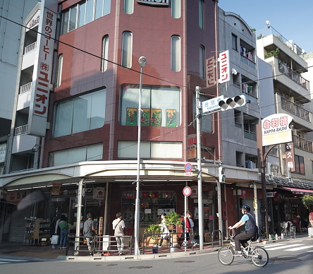 May 27, 2023 - Taito City, Japan: A cyclist and shoppers at a street corner on Kappabashi-dori Street in Nishiasakusa. The Kitchen Town neighborhood is famous for kitchen-related products. Spring afternoon in Tokyo.