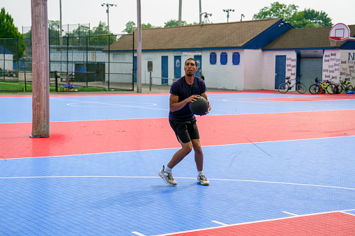 Latino man shooting baskets on playground d basketball court