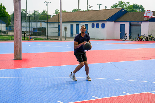 Latino man shooting baskets on playground d basketball court