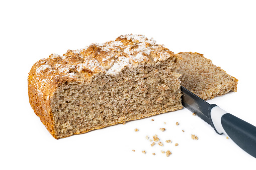A loaf of irish wheaten bread on white background. The bread is sliced with a knife.