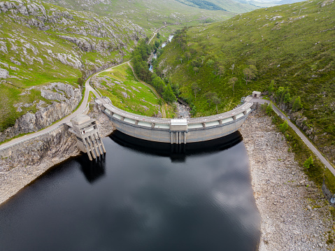 Aerial drone view of a hydro electric dam, in a remote location of the Scottish Highlands. Water levels are lower than normal, due to climate change, less rainfall and warmer weather than in previous years.