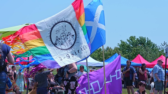 Display of flags at Two Spirits Pow wow. Pride flag with 2-Spirited Native American symbol. Iroquois Confederacy flag and Metis flag: Toronto, Ontario, Canada - May 27, 2023.