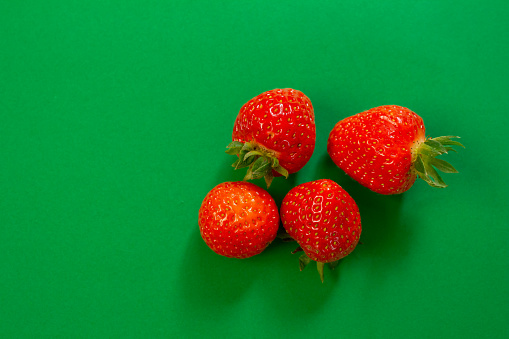 Strawberry isolated on green background. Top view, copy space.