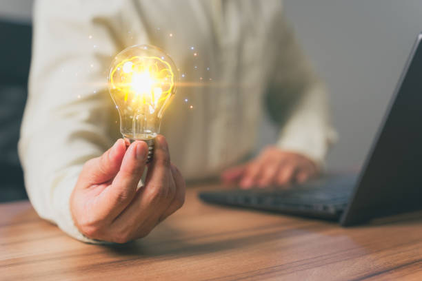 istock Man holding a light bulb while working on a computer laptop to think and generate new ideas through technological innovation and creativity. Idea inspired by online technology and innovation. 1503049059