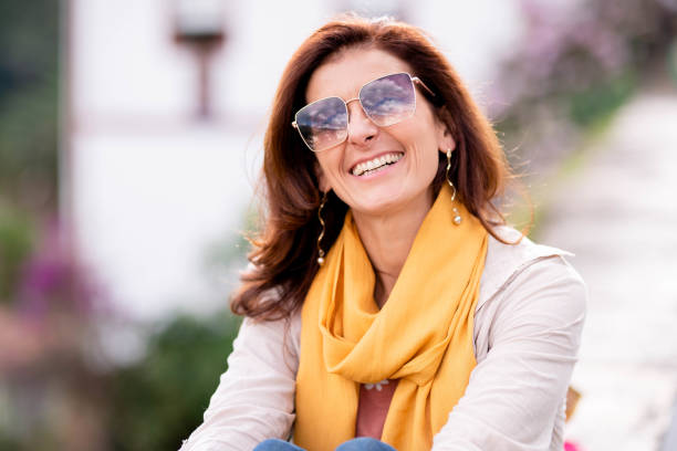 Portrait of a woman wearing sunglasses laughing while taking a break from exploring a town during a summer vacation