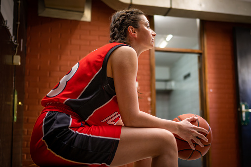 Rear view of a high school basketball player dribbling the ball down the court during a game.